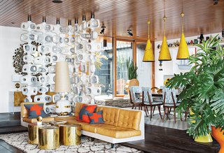 Jonathan Adler and Simon Doonan Go Trippy Contemporary on Shelter Island - Photo 7 of 12 - "The vibe feels cozy even though the living room is quite grand," Adler says. He made the room divider out of concrete and integrated the sofa with the step. Lee Jofa fabric covers the dining chairs and the pendants are vintage.