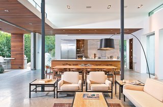 Custom walnut and stainless steel sheathes the kitchen, which is open to the living-dining area and the patio. The Twiggy lamp is by Foscarini; the sliding doors are from Fleetwood.