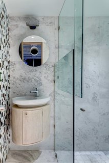 Rich Veracruz marble lines one wall of the bathroom, black-and-white tiles of various sizes clad another. 