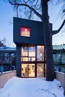 A City Home Grows Without Gobbling Up its Garden - Photo 1 of 4 - Determined not to destroy the home's limited connection to nature, Microclimat extended the addition only as far as a mature poplar tree in the rear garden. The cantilevered mezzanine is wedged between its trunk and boughs. 