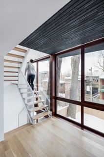 A City Home Grows Without Gobbling Up its Garden - Photo 2 of 4 - The expansion creates a narrow intermediary space between the yard and existing home. This sliver contains a light steel staircase and two new sun rooms for reading.