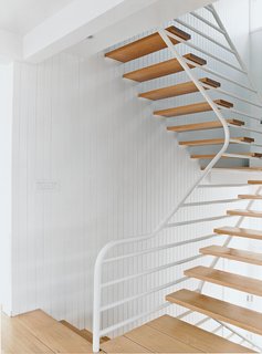 9 Unique Stair Railings - Photo 8 of 9 - In his first commission in the United States, renowned Modernist Walter Gropius designed this complex and masterful staircase and railing system in which the horizontal members of the railing support both the handrail and the stair treads. The painted white steel tubes appear flowing and air-filled, creating a grille that contrasts with the vertical panelling of the walls.