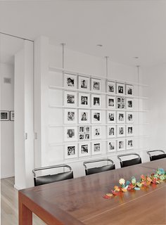 In the dining room, Mies van der Rohe chairs surround a custom-made cherry table. Black-and-white photographs of Sasseen's children and grandchildren are arranged systematically on the back wall.