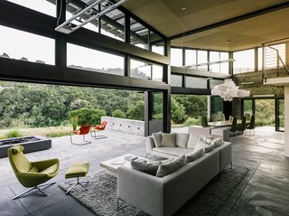 In the open living-dining area, a sofa by Antonio Citterio joins a Metropolitan chair and ottoman, all from B&B Italia. A Big Bang fixture from Foscarini hangs above the dining room table, designed by Feldman and surrounded by chairs from Ligne Roset.