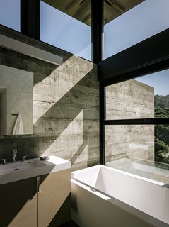 The bathroom in the guest pavilion takes advantage of the passive solar siting. "Detaching the roof from the walls allowed us to bring in light from the top," notes the architect. The custom vanity holds a Lacava sink; the tub is AquaStone from Aquatica.