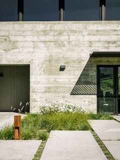 More native grasses set the tone near the generously sized concrete pavers leading to the entrance. "We didn’t want the planting to feel like a country cottage garden—that would have felt disconnected with the view behind it," Trainor says.