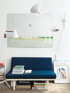 Aumas outfitted a vintage steel-frame sofa by George Nelson in navy blue fabric from Kvadrat and hung one of his own photos just above it. The lamp to the left of the sofa is a 1960s design found at a Lisbon flea market, and to the right of the sofa is a Two-Arms rotating sconce by the mid-century French designer Serge Mouille.