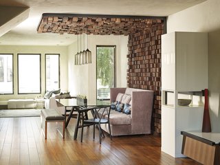 The dining room canopy was an idea inspired by something that the resident had seen while staying in a hotel. A steel frame holds a grid of solid walnut blocks. Two rows of LED lights, four pendants, and four pin lights illuminate the space, creating what Cooper calls "a shadowed textural effect."