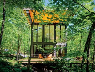 A Little Cabin Reaches Such Great Heights - Photo 1 of 4 - A cantilevered cabin designed by R D Gentzler blends into the forest, even as it hovers above a 20-foot drop-off. Its south face is almost entirely glass, but a roof canopy limits solar gain. "We sit on the deck all afternoon watching the trees, and the time just flies by," says resident Maricela Salas.
