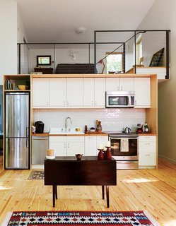 A Little Cabin Reaches Such Great Heights - Photo 4 of 4 - The kitchen and lofted guest bedroom take cues from urban living—including an apartment-size Summit refrigerator. The cabinets are IKEA and the tile is by Heath Ceramics. 