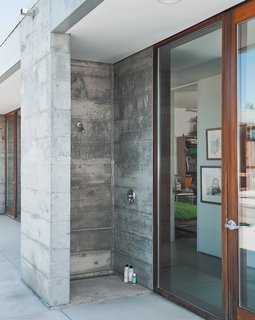 An outdoor shower is made from one complete concrete module—a visual demonstration of how the entire house was built. 