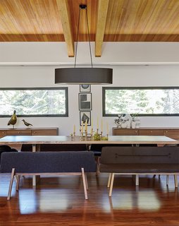 The Ski Retreat for All Seasons - Photo 3 of 10 - An oversize oval black linen shade from Dogfork Lamp Arts hangs above a table Maca created out of a wood slab from West Marin-based artisan Evan Shively of Arborica. The bench seats are De La Espada; the brass candelabrum is vintage, sourced from 1stDibs. The credenzas are Bo Concept. 