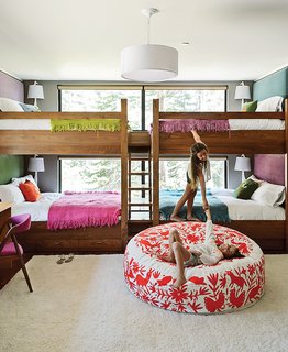 The Ski Retreat for All Seasons - Photo 5 of 10 - In the kids’ bunk room, Maca designed walnut beds with built-in storage and fabric headboards, and covered each one in hand-knit blankets by Marcela Rodriguez-Chile. The giraffe sconces are from Jonathan Adler. The girls play on a hand-embroidered Olli lounger from Heath Ceramics. 