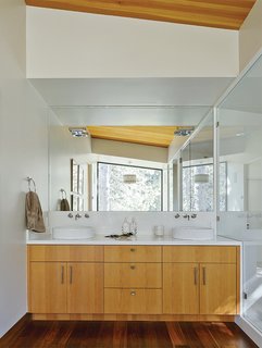 The Ski Retreat for All Seasons - Photo 9 of 10 - Talo Mini chrome sconces from Artemide installed atop the mirror in the master bathroom effectively disappear, becoming what Maca calls "subtle 3-D sculptures." The Neo Blanco vanity, from Porcelanosa, is clad in the same Douglas fir as the ceiling. The IQ faucets are from Jado. 