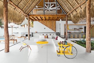 Bursts of Yellow and Indoor Gardens Are Just Two Reasons to Love This Home - Photo 1 of 5 - The living-dining area of a beach house designed by El Salvador firm Cincopatasalgato features a custom bar cart by local designers Claudia & Harry Washington, a built-in sofa, and an Ikono chair and Circa low tables by The Carrot Concept. 