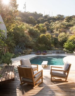 Low retaining walls form a subtle barrier between the backyard and the surrounding vegetation. Mandy Graham designed the armchairs and lounges.