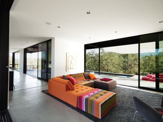 The Mikado 2 sofa by Hans Hopfer for Roche Bobois is a bright and cheery centerpiece in the otherwise sedate living room. The nubby wool Photon rug from Design Within Reach warms up the expanse of concrete. The framed drawing is by the Los Angeles–based artist Daniel Brice. Huge sliding doors open the house to the outdoors and virtually double the Burtons' living space.