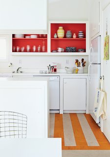 How a Smart Interior Design Saved This House - Photo 5 of 9 - In the kitchen, Angle removed the cabinet doors and applied a coat of Poppy Red paint by Benjamin Moore, and put down a striped linoleum floor to brighten the space.