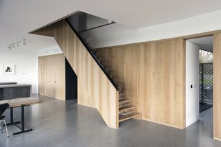 A palette of natural materials is employed in both the interior and exterior. An oak wall and staircase, designed by Jeremy Pitts, join a floor made of gray terrazzo tile. 