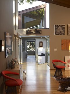 The long hallways do as much to delineate the home's space as the windows do. A pair of Wire series chairs for Knoll by Warren Platner add a space-age modern feel to the home's leafy vibe. 