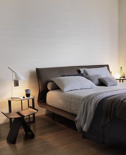 Nearly every piece in the apartment has a pedigree. An AJ table lamp by Arne Jacobsen sits on a Domino table by Nicola Gallizia beside a Night&Day bed by Patricia Urquiola for Molteni&C. The Butterfly stool is a 1954 design by Sori Yanagi.
