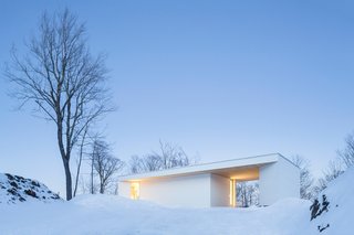 This Snowbound Pad Will Actually Make You Miss Winter - Photo 1 of 3 - Seen from the street, the Nook Residence's white-painted wood exterior vanishes against a snowy backdrop. 
