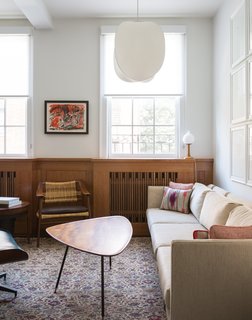 "Our love for Japanese design, and respect for it as a precursor to the midcentury aesthetic, came into the design of the radiator covers," architect and designer Suchi Reddy says. In the living room, a sofa by esteemed midcentury designer Milo Baughman joins a Bambi lounge chair by Norwegian designers Rolf Rastad and Adolf Relling. The pendant light is the Mori Leaf model from Rich Brilliant Willing. Architect Matthew Viederman designed new finishes for the floors, bathrooms, and kitchen. Reddy's team spearheaded the furniture selection as well as the millwork at the radiators.