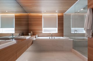 The bathrooms saw the least significant changes. In the one nearest to the master bedroom, the shower and tub are original. White oak paneling provides continuity between the newly renovated spaces. 