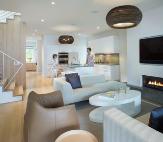  In the living room, a custom chaise by Shimna and an Archibald Gran Comfort chair by Poltrona Frau surround a custom lacquer coffee table by BenchCraft.The lights, made from recycled cardboard, are by Seattle design studio Graypants. 
