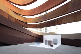 The work's overlapping layers of color and transparency respond to the patterns of light and shade created by the surrounding architecture.