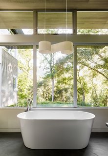 In the master bath, a Duna pendant by El Torrent hangs above a Blu Stone tub. 