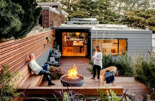 After raising the rear patio to the level of the kitchen, the team reused the original redwood decking and supplemented it with recycled pieces from other projects. Recessed planters punctuate a garden wall. Scott and Regina warm themselves by a Solus fire pit on chilly evenings. 