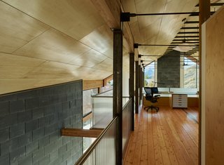 In the main house, a lofted upper level contains the master suite and an office area, furnished with an Aeron chair from Herman Miller.