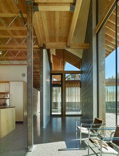 The building frame was prefabricated in Iowa using steel members and stress-tested SDS lumber—elements left exposed in the final design. A pair of LC1 chairs from Cassina create a seating area off the kitchen.