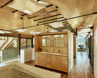 In the master bathroom, custom vanities made of Baltic birch face a Soiree tub by Toto. Paper lanterns from IKEA illuminate the lofted level.