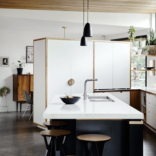 Using laminates trimmed in Victorian ash for the island cut costs. The white cabinets hide the refrigerator <span style="line-height: 1.8;">and separate the kitchen from the dining room.</span><span style="line-height: 1.8;"> </span>
