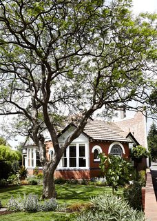 The house is located on a tight site surrounded by a brick wall.