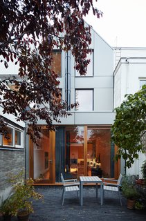 Because replacing the foundation would require significant alterations to the facade, the architecture team chose not to restore the original cottage. Equitone panels clad the new structure's contemporary rear; mahogany-framed doors made by a local joiner lead to a patio with a Falster dining set from IKEA. 