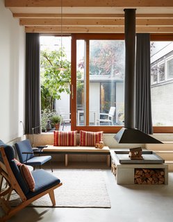 A band of precast concrete, which holds a custom bench, wraps around the downstairs living area. The striped cushion fabric was purchased in Antwerp. A wood-framed AP71 lounge chair by Hans Wegner and a seat by Wim Rietveld, the son of famed Dutch designer Gerrit Rietveld, outfit the space. Underfloor heating installed throughout the house allows for a flexible layout: "There aren’t any radiators cluttering up the rooms," Jeffries explains.