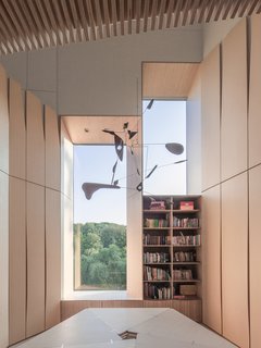 What’s the Twist Behind This Home’s Sinuous Staircase? Ordinary Plywood - Photo 1 of 14 - In renovating a historic brick home for family friends in Washington, D.C., architect Nader Tehrani of NADAAA used ordinary plywood to reconceive the central staircase. Lined with a series of striated, geometric panels, the resulting structure is lit by a polygonal skylight above. Tehrani also designed the Pentavola table—featuring five sides, one for each member of the family—which they use as a communal workspace on the second-floor landing.