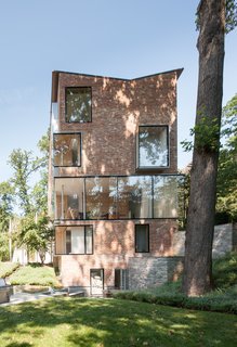What’s the Twist Behind This Home’s Sinuous Staircase? Ordinary Plywood - Photo 5 of 14 - For the southeast-facing facade, which is concealed from street traffic, Tehrani opted for transparency, repositioning bricks to place a sculptural collage of protruding box windows and a glass expanse. 