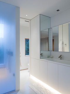 What’s the Twist Behind This Home’s Sinuous Staircase? Ordinary Plywood - Photo 7 of 14 - The capacious master suite includes a bathroom with a glass-enclosed shower, under-lit cabinetry, and a box window that looks south toward the garden and pool. The shower fixture and faucet are by Agape. Organic, undulating forms frame the stairwell that connects the first floor and garden floor.
