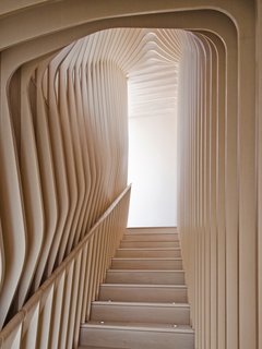 Organic, undulating forms frame the stairwell that connects the first floor and garden floor. Though they give the appearance of bent plywood, each curved layer of the ribbed corridor was constructed with flat, laminated cutouts, including the rounded hand rail. 