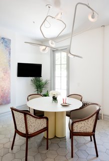 Modern Becomes Eclectic in This Renovated Brooklyn Townhouse - Photo 4 of 13 - The mashup of styles is as diverse as the range of RBW designs that peppers the interiors, including the snaking Palindrome 6 chandelier made from a modular, tubular-steel frame. It hangs in the kitchen, above a Corian-and-plywood dining table. Lyons reupholstered the vintage Brickel dining chairs by the late American designer Ward Bennett—who designed with an eye for sensual minimalism—in leather and Rain Dance linen by Schumacher; a randomized pattern of custom cement hex tiles by Original Mission Tile lines the floors.