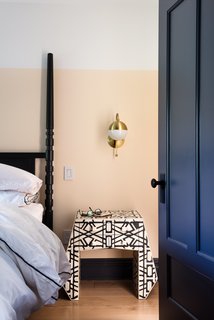 Modern Becomes Eclectic in This Renovated Brooklyn Townhouse - Photo 12 of 13 - In the master bedroom, expanses of white and peach paint play against the geometric lines of an inlaid-bone nightstand from Anthropologie. The traditional four-poster bed is from West Elm; the brass Cedar & Moss sconce is from Rejuvenation. 