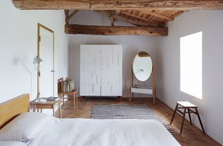 Over a Decade, Two Furniture Designers Reimagine a 300-Year-Old Barn - Photo 3 of 11 - A white Alba armoire by Pinch stands next to the brand’s Iona cheval mirror in a second-floor bedroom. The Moroccan rug was found in Paris; the Malm bed from IKEA was a budget buy.