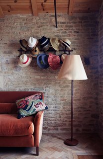 Over a Decade, Two Furniture Designers Reimagine a 300-Year-Old Barn - Photo 4 of 11 - In a cozy nook the family calls the "snug," hats hang from a Thonet rack above a Noelle sofa by Pinch, which is upholstered in orange velvet by Kravet.