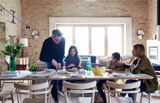 Over a Decade, Two Furniture Designers Reimagine a 300-Year-Old Barn - Photo 6 of 11 - The family gathers at an early prototype of the Achilles table from the Pinch collection. Surrounding it are chairs that were designed by Russell and produced by Ercol for London’s Holland Park School. The couple built the doors and windows themselves.