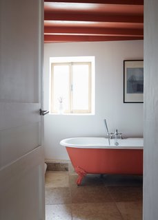 Over a Decade, Two Furniture Designers Reimagine a 300-Year-Old Barn - Photo 9 of 11 - A coat of Orange Aurora paint by Little Greene enlivens an Astonian Rimini clawfoot tub.