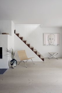 The wicker PK22 lounge chair and a foldable PK91 stool made from steel and canvas sit by the staircase on the first floor. 